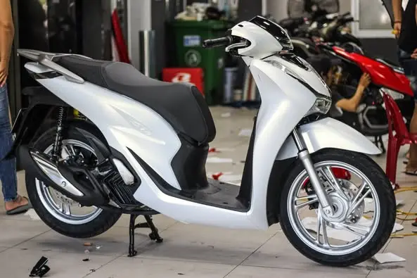 Xe Honda SH màu trắng ngọc trai đang đỗ dưới ánh nắng