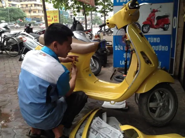 Một người thợ đang kiểm tra chi tiết một chiếc Vespa cũ